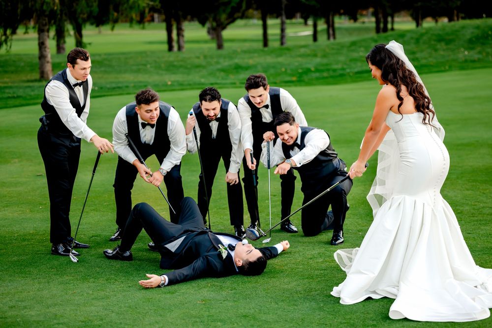 Wedding party members pose playfully on green grass for creative photo series.