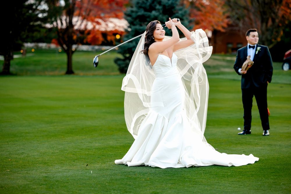 Newlyweds dance and twirl across a lush green lawn during an outdoor autumn wedding celebration.