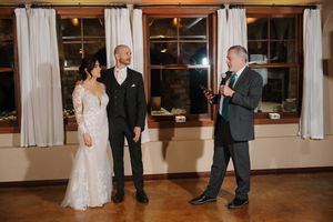 Wedding guests dance together on a wooden floor during an evening reception celebration.
