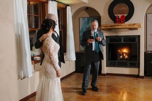 Wedding couple dances together in an elegant room with hardwood floors and white walls.