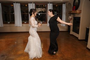 A couple dances together at a wedding reception on a polished wooden floor in a spacious venue.