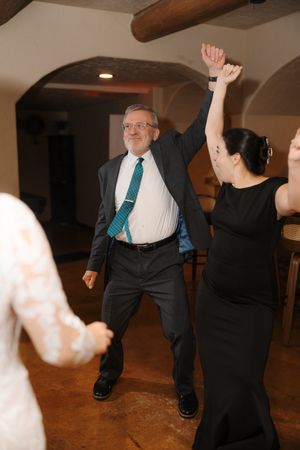 People dancing and having fun at a party on a rustic wooden floor with exposed ceiling beams.