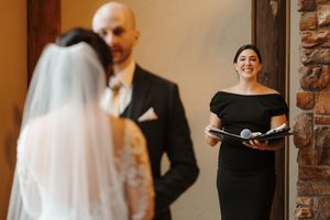 Couple exchanging vows during an intimate indoor wedding ceremony with exposed brick walls.