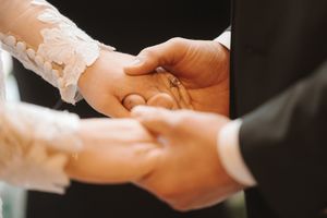 Close-up view of hands exchanging wedding rings during a traditional ceremony.