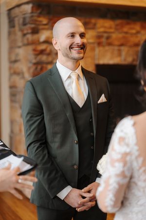 First look reaction between bride and groom at a rustic venue with stone walls and warm lighting.