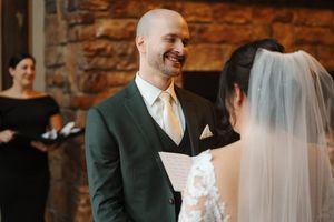 A romantic wedding ceremony moment captured in warm lighting with rustic brick walls in the background.