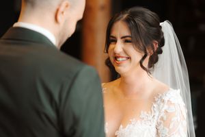 A bride and groom share an intimate moment during their wedding ceremony in soft natural lighting.