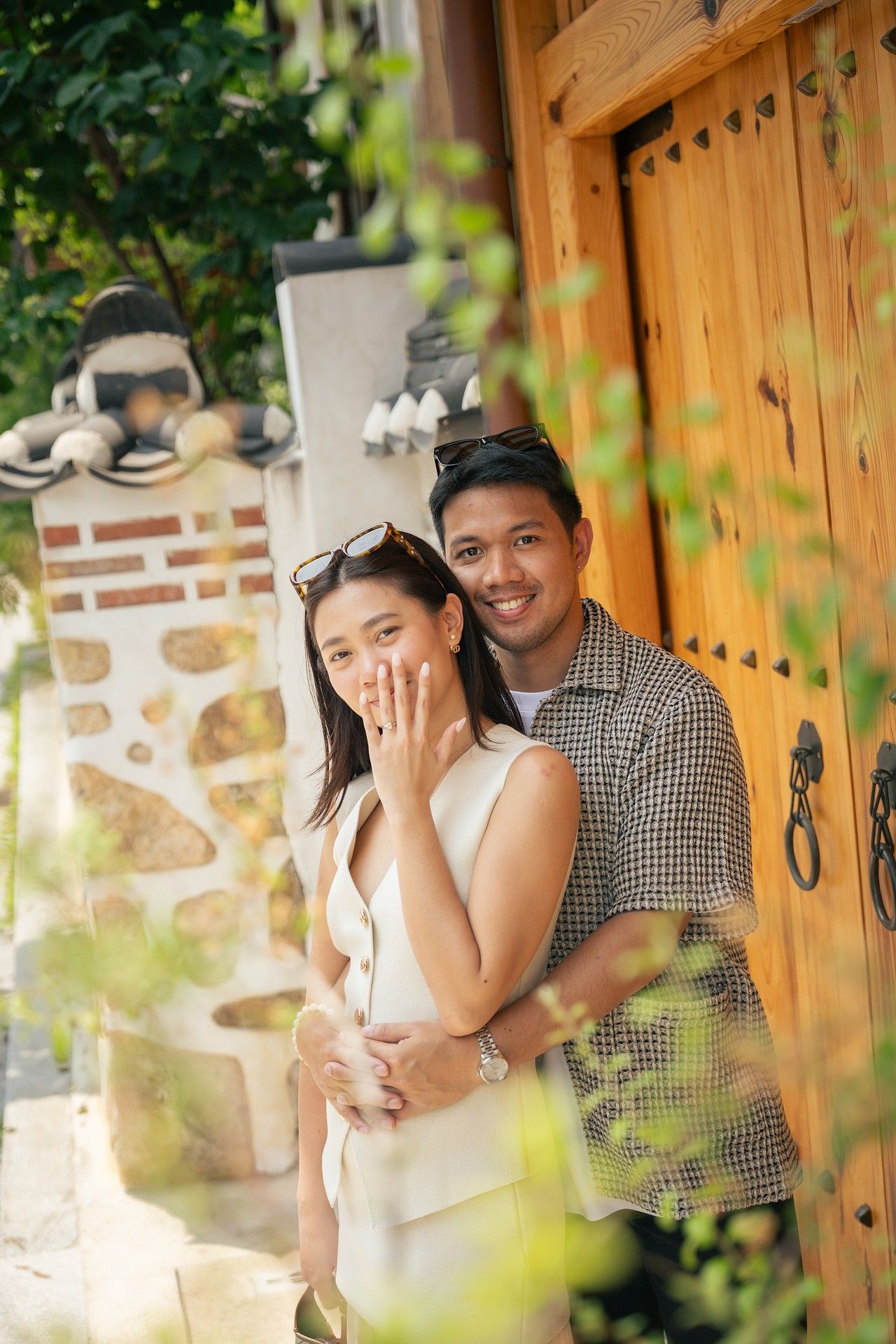 A couple shares intimate moments together against a rustic wooden door and stone wall backdrop in an outdoor setting.