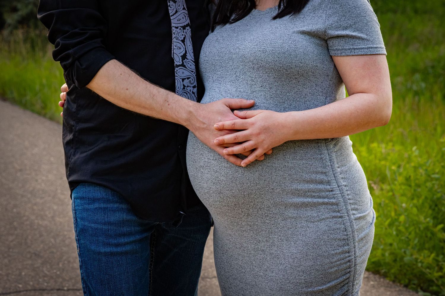 a pregnant woman and her husband hold her baby bump.