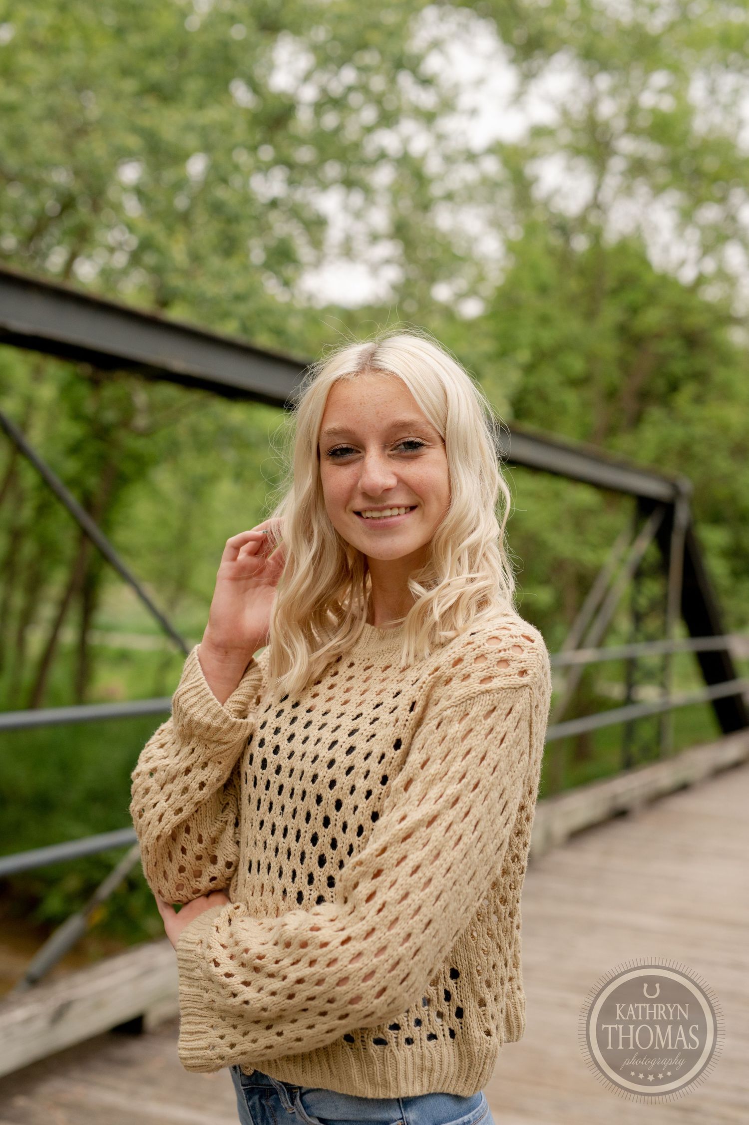 Natural outdoor portrait featuring cream open-weave sweater against green foliage.