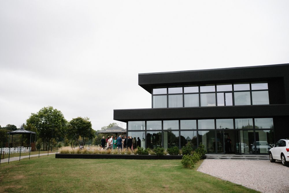 Modern black architectural venue building set against a cloudy sky.