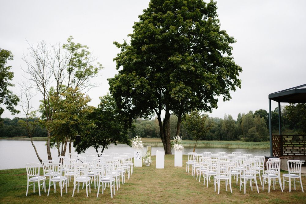 White ceremony chairs arranged in rows on a hilltop overlooking natural scenery.