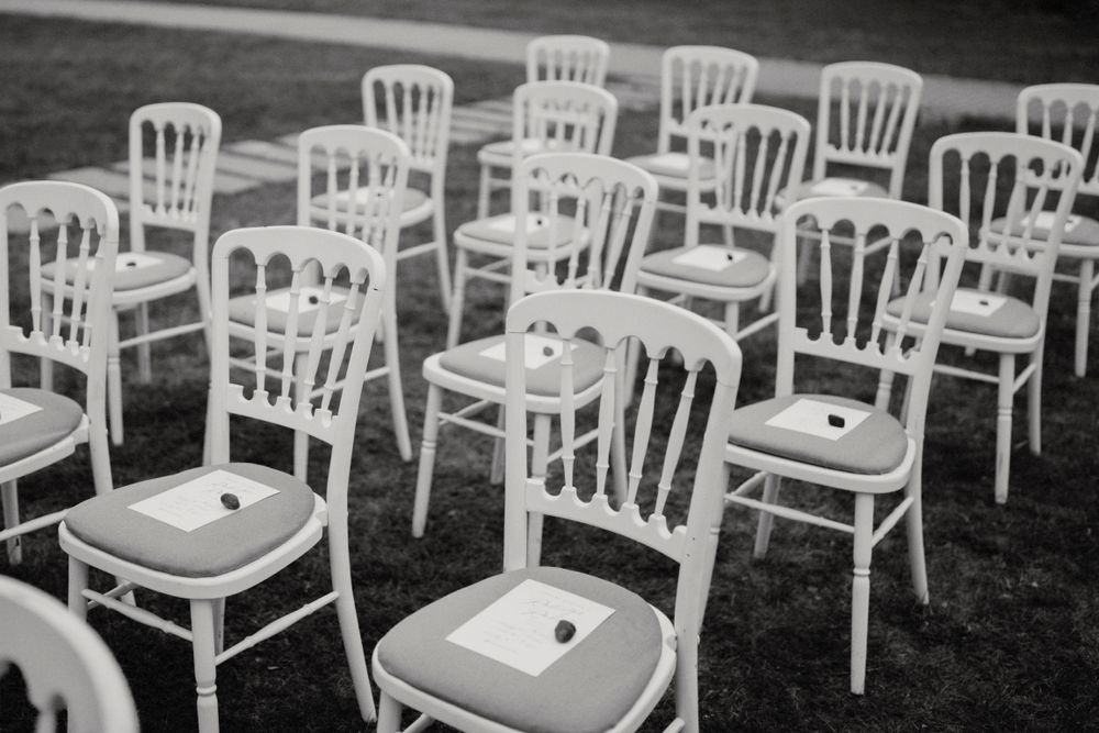 White wooden chairs arranged in rows for an outdoor wedding ceremony.