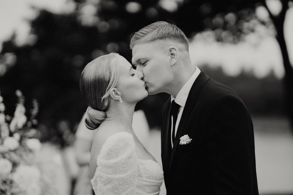 Black and white romantic wedding portraits against natural outdoor backdrop.
