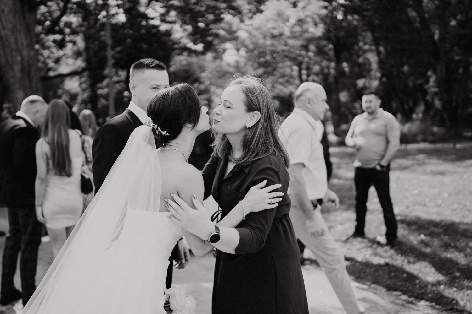 Black and white photo capturing emotional embrace at outdoor wedding celebration.
