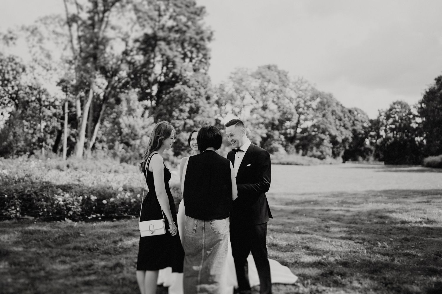 Black and white photo of wedding guests mingling in an outdoor garden setting.