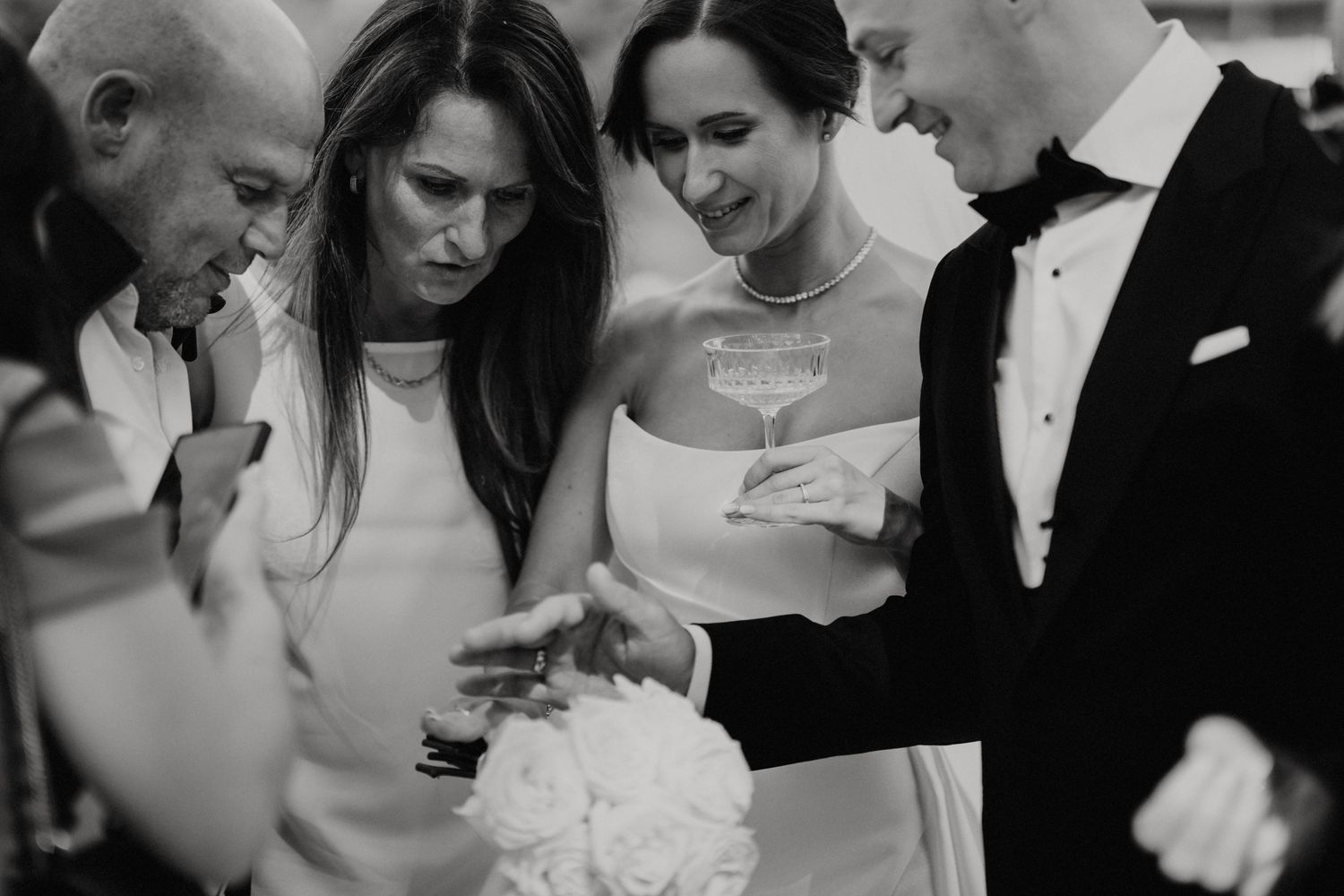 Black and white photo of wedding guests looking at mobile phones during the celebration.