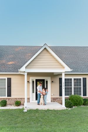 Beige ranch-style house with front porch and black shutters.