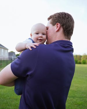 Intimate parental bonding moment captured outdoors in a residential backyard setting.