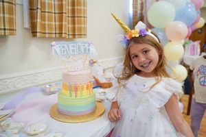 Birthday celebration with a festive unicorn-themed rainbow cake and party decorations.