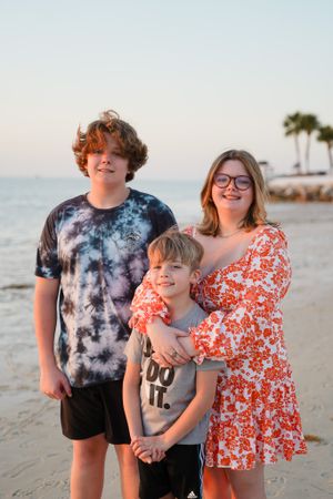 Family group enjoying sunset together on a beach with palm trees in background.