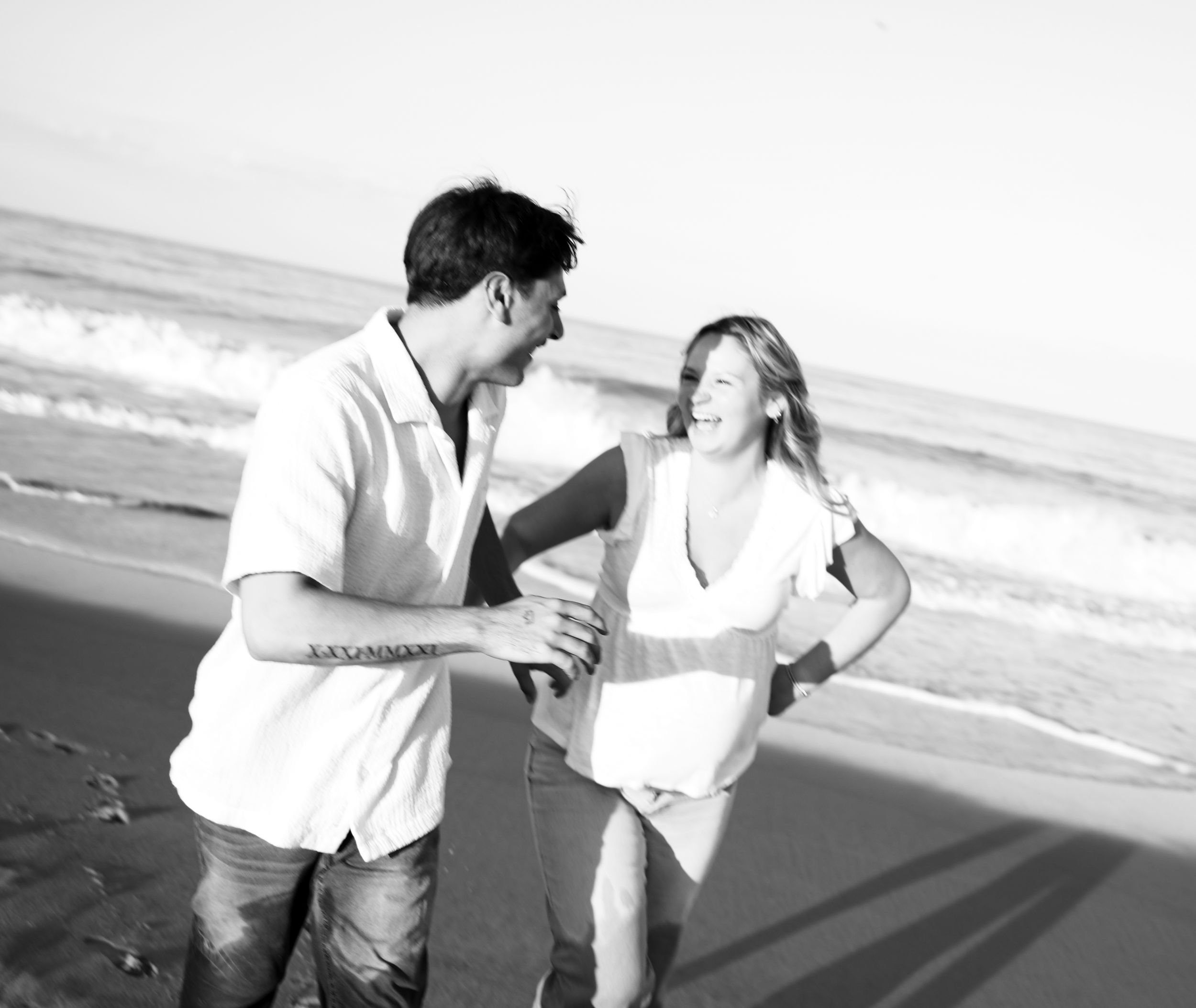 A series of black and white photographs showing a romantic couple embracing and walking along a beach.