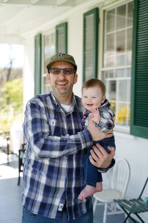 Sweet candid moment captured on a bright white porch with classic green shutters.