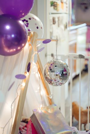 Party decorations with purple balloons and disco ball create festive atmosphere.