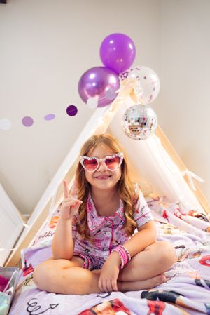Playful scene inside decorated tent fort with purple balloons and disco ball.