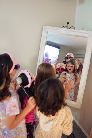 Group looking in mirror during party with pink and white decorative backdrop.