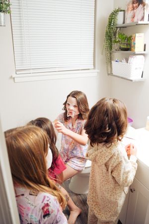 Intimate gather in bathroom with plants and white decor visible in background.