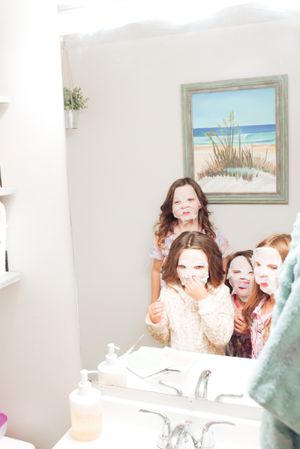 Party scene with beach artwork visible on wall and bathroom mirror reflections.
