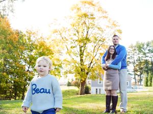 Family enjoying a sunny autumn day outdoors with fall foliage and golden sunlight in a park setting.