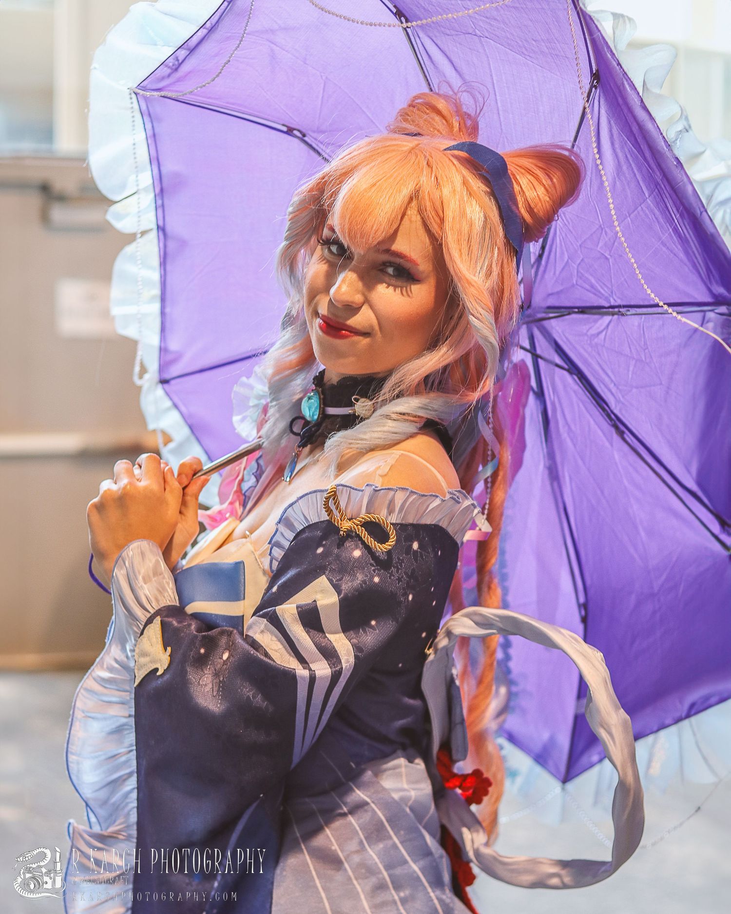 Cosplay portrait with purple umbrella and peach-colored wig in bright setting.