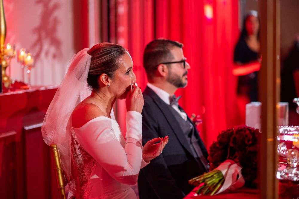 Wedding celebration moment captured during reception with red curtain backdrop.