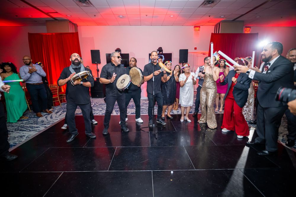Wedding band performs for crowd of guests on dance floor with dramatic red lighting.