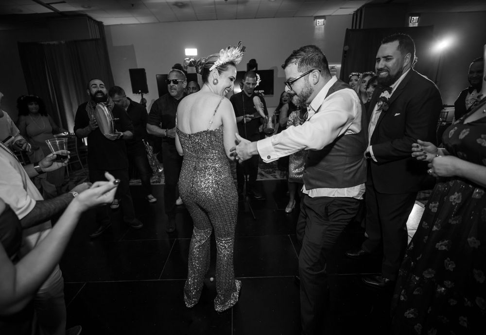 Couples dance together on dark dance floor during wedding reception celebration.