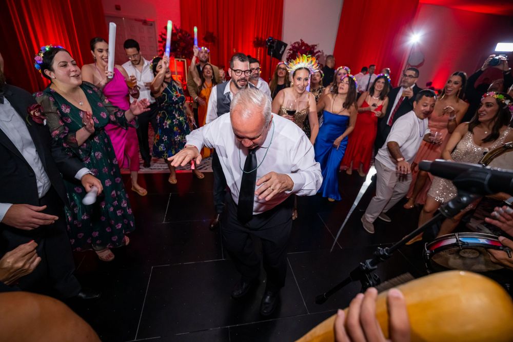Party crowd dances under red lighting at a lively indoor celebration.