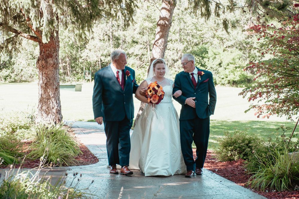 A beautiful outdoor wedding ceremony procession walking down a garden path.