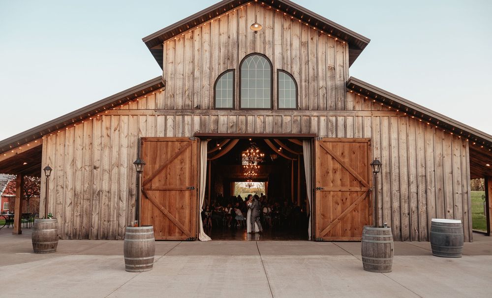 Rustic wooden barn wedding venue with large open doors and wine barrels at the entrance.