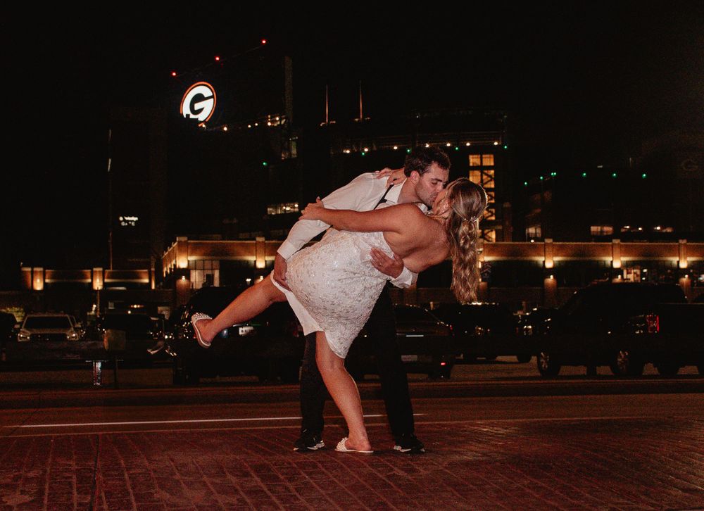 Romantic nighttime dance dip pose in front of city lights and buildings.