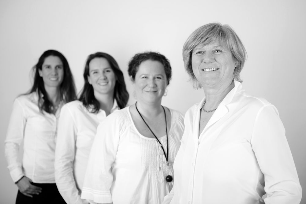 Group of people in white clothing posing together for a casual studio portrait.