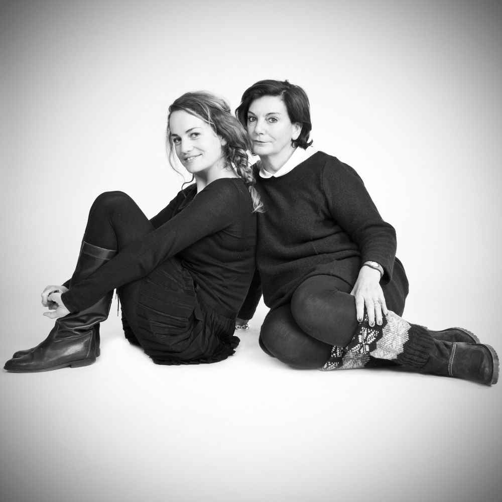 Artistic black and white photos of two people lounging together in dark clothing against a white backdrop.