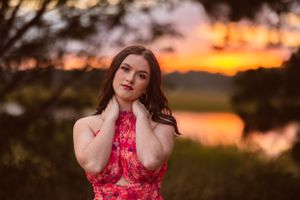 A dreamy portrait in a red dress against a glowing sunset backdrop at golden hour.