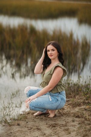 Casual outdoor portrait by a marsh at sunset in casual denim and olive top.