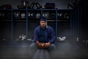 Student athlete seated in school locker room wearing navy uniform.