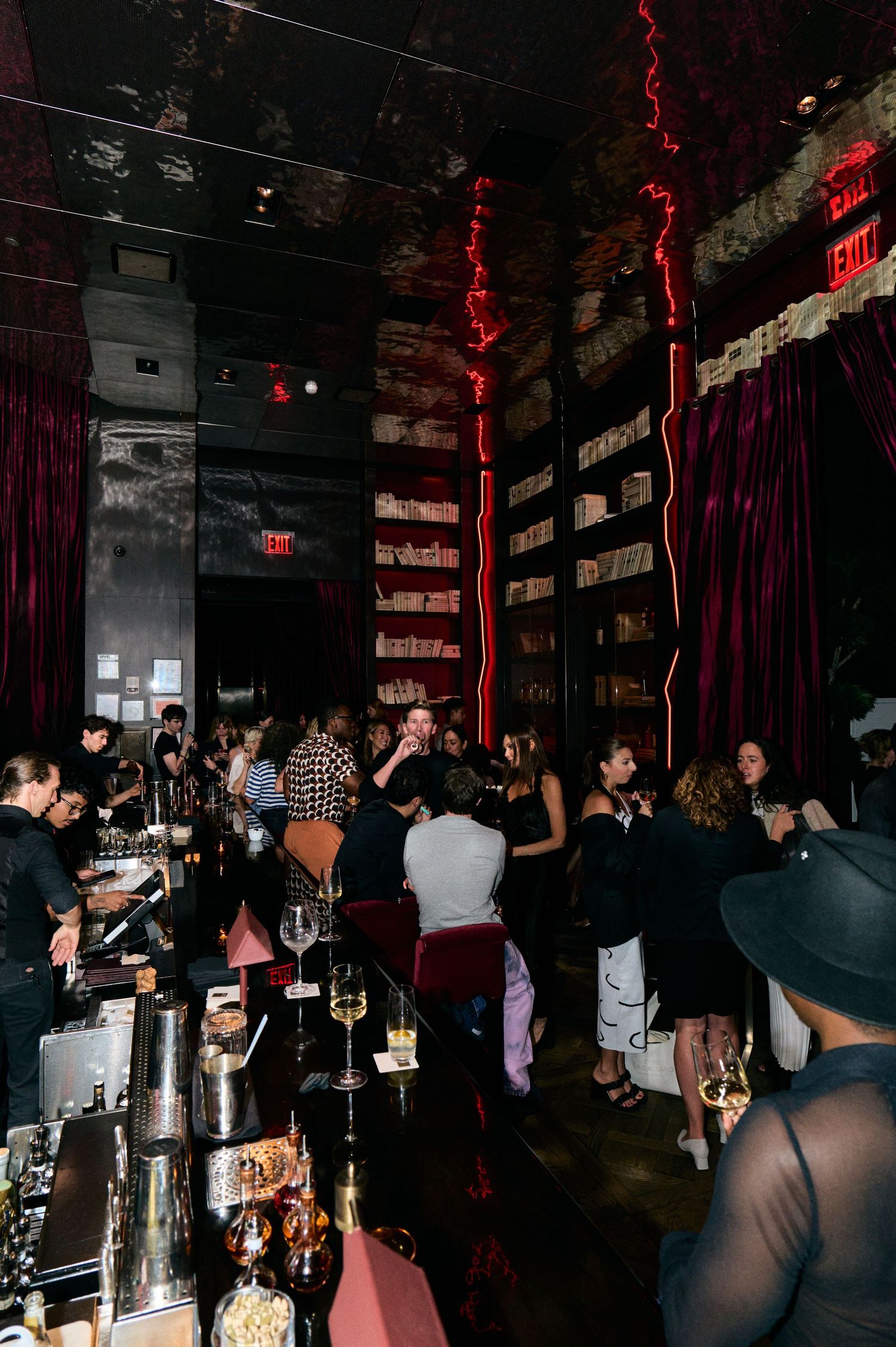 Crowded nightclub bar scene with red mood lighting and dark ambiance.