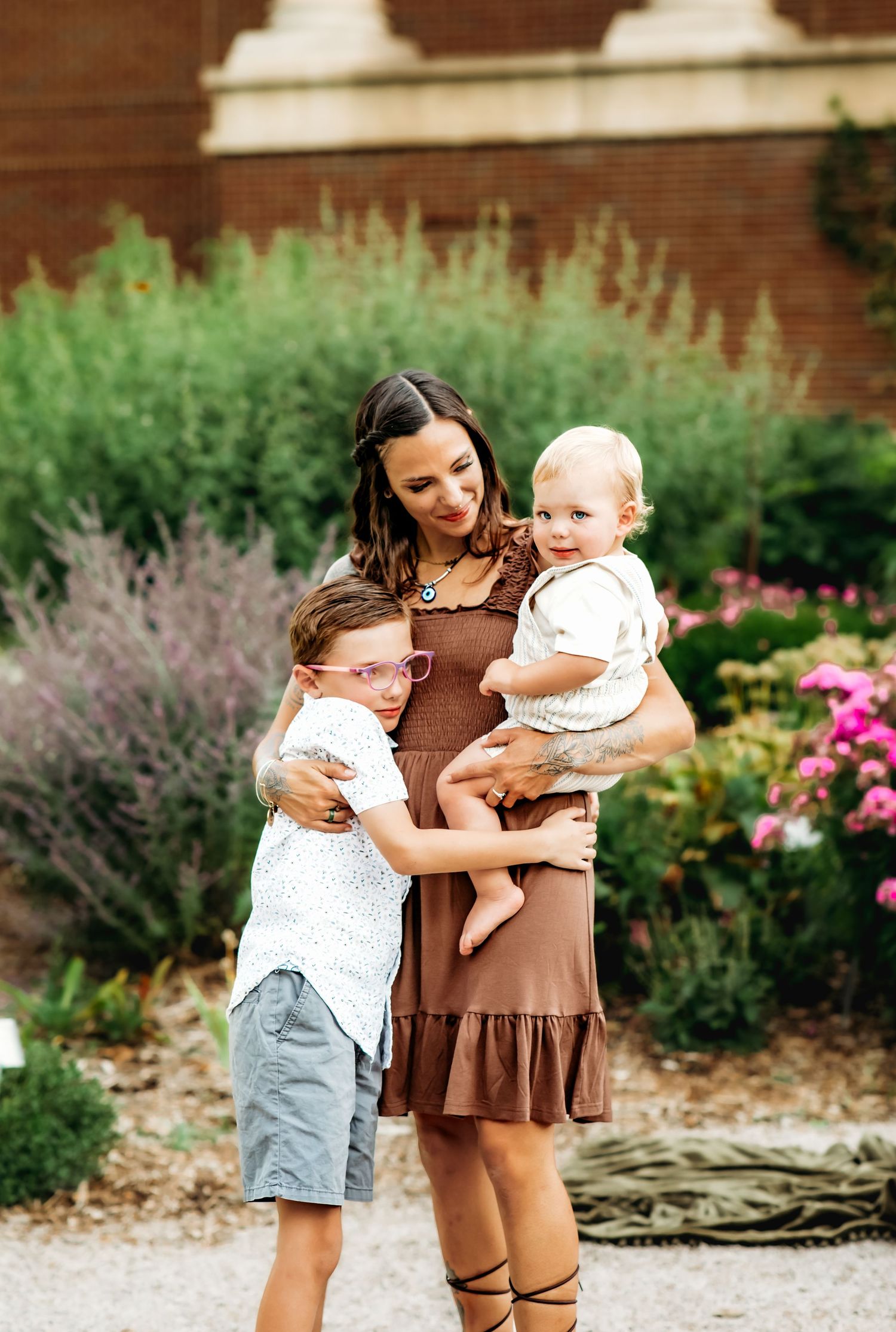 A heartwarming family moment captured in a garden setting with blooming flowers and greenery in the background.