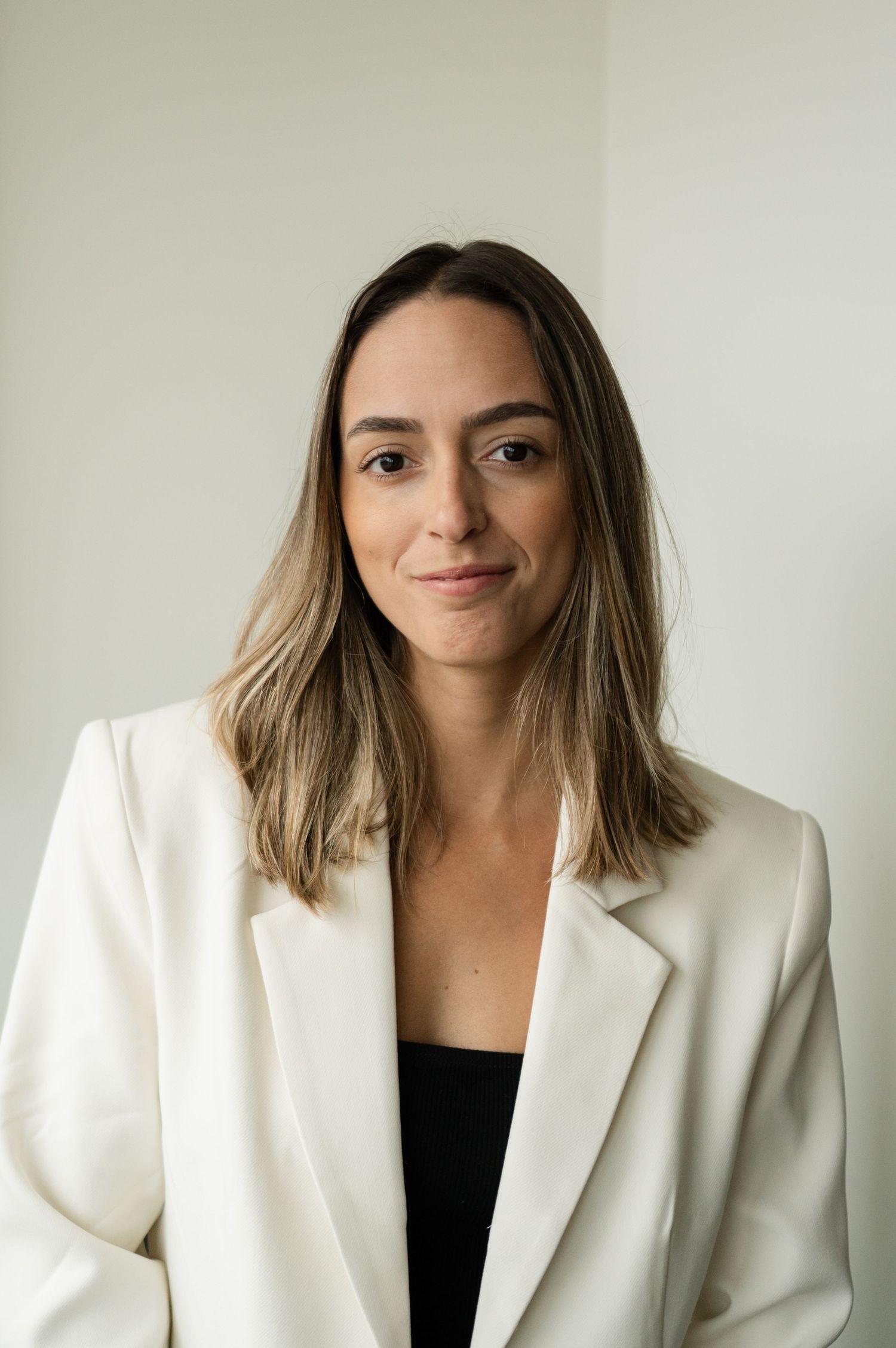 Professional headshot series showing different poses in white blazer against neutral background.