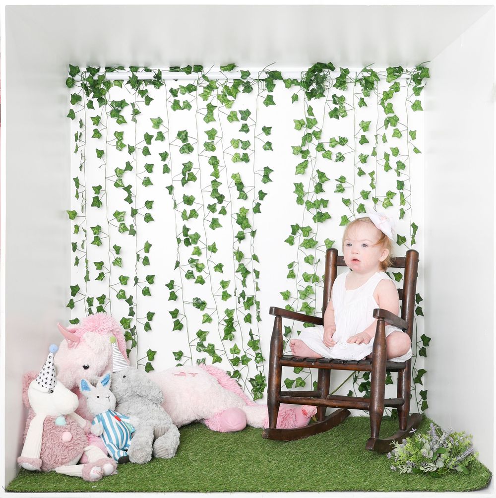 Whimsical nursery scene with green ivy wall, rocking chair, and plush animal toys.